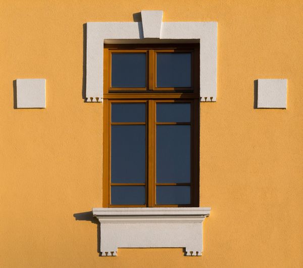 Hausfassade mit mineralischem Untergrund in Orange und Weiß gestrichen.